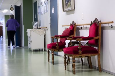 Kuvan käytävällä on kaksi vanhan ajan nojatuolia, joissa on arvokkaan punaiset pehmusteet.