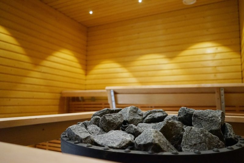Etualalla saunan kiukaan kiviä kiukaalla, takana näkyy puisen saunan seinää ja lauteita.