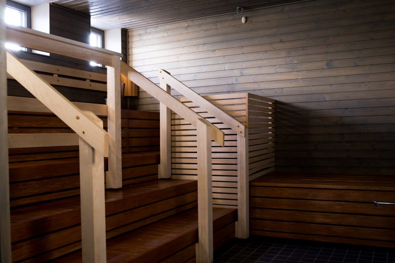 Kuvassa on tyhjä ja uuden näköinen sauna. Lauteet ja seinä ovat tummempaa puuta kuin kaiteet.