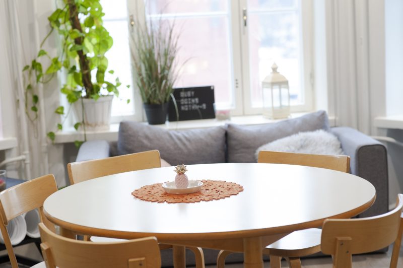 Sisäkuva Saarnituvan yhteistilasta. Lähikuvassa pyöreä pöytä, jolla on pieni ananaskoriste. Taustalla näkyy sohva ja ikkunalaudalla olevat viherkasvit.
