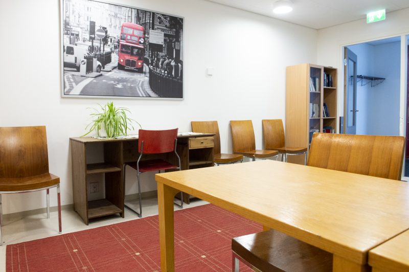 Wäylän olohuonekuvassa näkyy kaksi pöytää ja seinustaa vasten odottaa tuoleja. Nurkassa on kirjahylly ja seinällä on suuri taulu Lontoon katukuvasta.