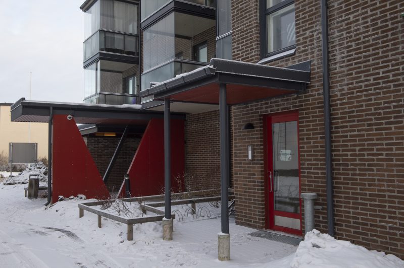 Ulkokuva Wäylän sisäänkäynnistä. Rakennus on tummapunertavaa tiiltä, sisäänkäynnin yhteydessä punaisia yksityiskohtia. Maassa on lunta.