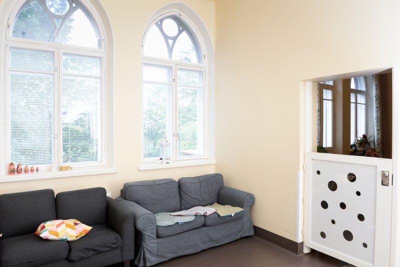 Kuva olohuoneesta, jossa kaksi harmaan sävyistä sohvaa kahden ison kaarevan ikkunan edessä.