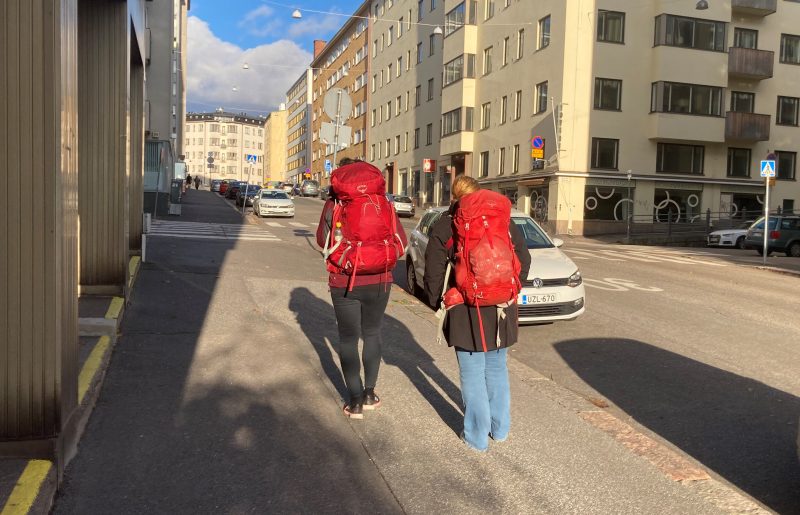 Kaksi ihmistä punaiset reput selässä kadulla. 