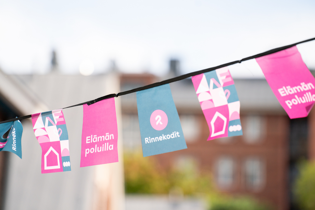 Colorful flags hanging on a rope. Flags are having Rinnekodit colors and signs on them.