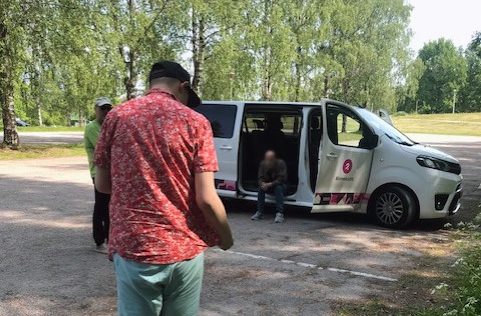 Punapaitainen mies kävelemässä kohti avoinna olevaa valkoista pakettiautoa.