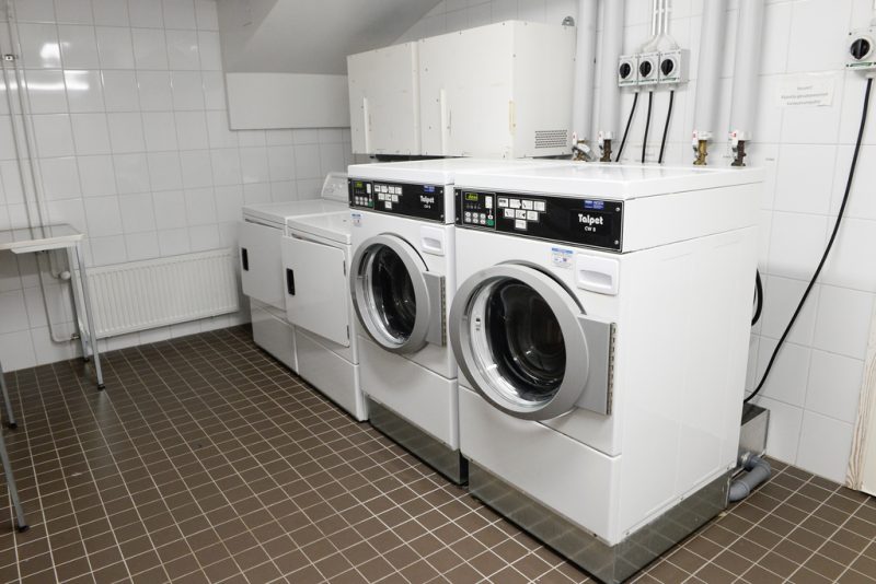 Pesutuvassa kaksi isoa pyykinpesukonetta ja kaksi kuivuria rivissä.