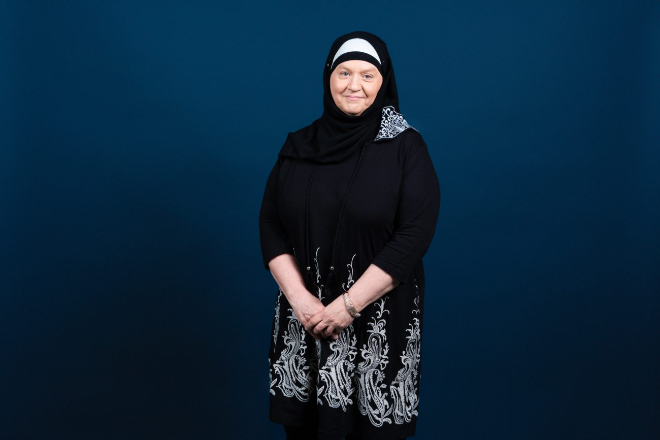 Nainen katsoo hymyillen kameraan.