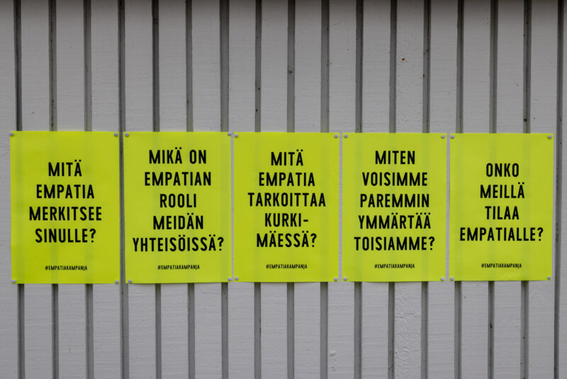 Neonkelaisia julisteita seinällä, julisteissa empatiin liittyviä tekstejä. 