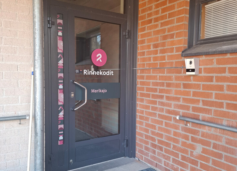 Rinnekodit Merikajon sisäänkäynnillä lasinen ulko-ovi.