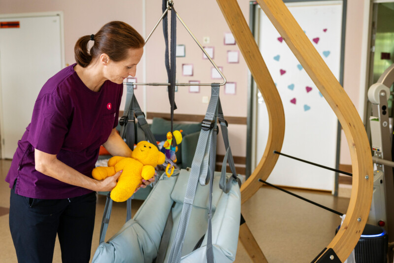 Nainen laittaa keltaista nallea hoitokehtoon.