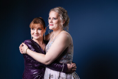 Kaksi naista juhlapuvuissa halaa toisiaan.