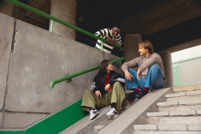 Nuoria istuu ulkona betoniportailla.