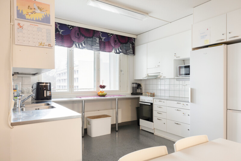 Valkoisen sävyinen isohko keittiö.