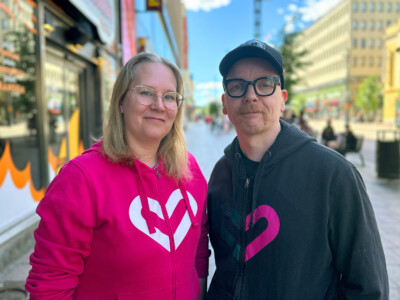 Kaksi henkilöä seisoo kadulla ja katsoo hymyillen kameraan.