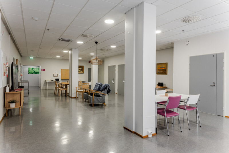 Avara yhteinen oleskelu- ja ruokailutila, jossa on pöytäryhmiä ja nojatuoleja.