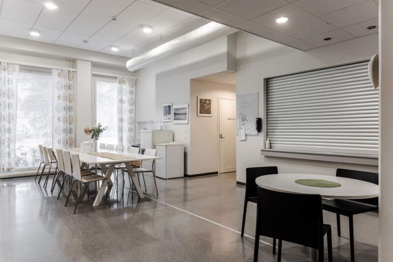 Valoisa yhteinen ruokailutila, jossa on pitkä pöytä tuoleineen ja pyöreä pöytä.